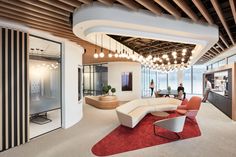 an office lobby with large curved couches and red rugs in front of windows