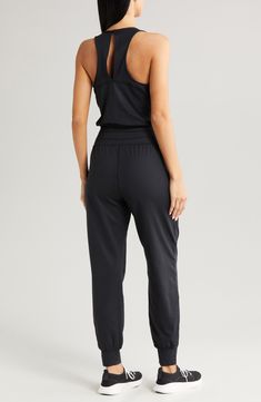 Perfect for low-impact studio workouts or just lounging around, this sporty jumpsuit is made from easy-moving stretch fabric with sweat-wicking properties. The relaxed fit is detailed with a keyhole racerback for added breathability. 60" length; 29" inseam; 10" leg opening (size Medium) Back keyhole with button-and-loop closure V-neck Sleeveless, with cutaway shoulders Front slant pockets Elastic waist Banded cuffs Moisture-wicking fabric engineered for dryness and comfort 85% polyester, 15% ela Casual Stretch Jumpsuits And Rompers For Training, Sleeveless Activewear With Elastic Waistband For Workout, Stretch Jumpsuits And Rompers With Elastic Waistband, Casual Black Jumpsuits And Rompers For Gym, Casual Black Sports Jumpsuits And Rompers, Casual Black Jumpsuits And Rompers For Sports, Athleisure High Stretch Jumpsuits And Rompers For Loungewear, High Stretch Athleisure Jumpsuits And Rompers For Loungewear, Athleisure Stretch Jumpsuits And Rompers For Yoga