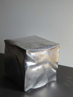 a silver object sitting on top of a table next to a white wall and floor