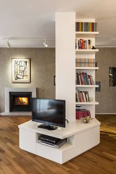 a living room with a television and bookshelves on the wall next to a fire place