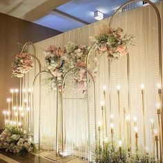 an elegant wedding setup with flowers and candles on the side wall, surrounded by gold arches