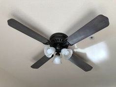 a ceiling fan with three light bulbs on it in a room that has white walls