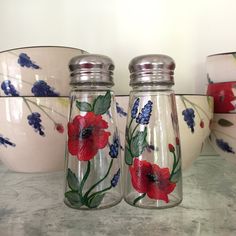 three glass jars with flowers painted on them