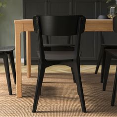 a dining room table with chairs and a vase on the floor in front of it