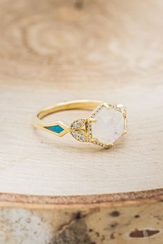 a gold ring with white and blue stones on it sitting on top of a wooden table