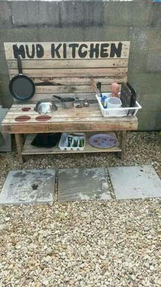 a wooden bench sitting on top of a sidewalk next to a pot and pans