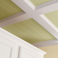 a kitchen with white cabinets and green painted ceiling tiles on the walls, along with an open cabinet door