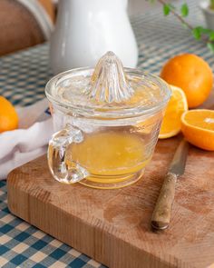 a glass jar filled with liquid sitting on top of a cutting board next to oranges