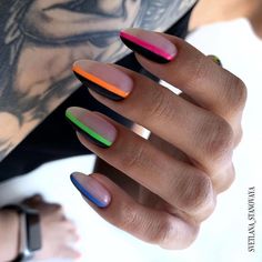 a woman's hand with multicolored nail polish on her nails and tattoos