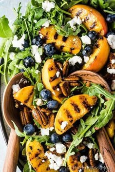 a salad with grilled peaches, blueberries and feta cheese on top