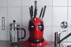 a red deadpool knife holder with knives sticking out of it's centerpiece