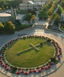 an aerial view of a circular garden with flowers in the center and a cross on it