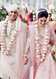 the newly married couple is walking down the aisle with flower garlands around their necks