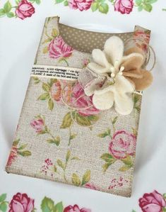 a white plate topped with a flower on top of a floral covered cloth tablecloth