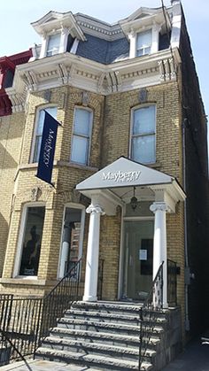 an old brick building with stairs leading up to the front door and entry way that has a white awning over it