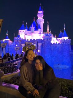 two women pose for a photo in front of the castle