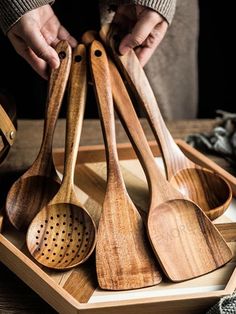 wooden utensils are arranged in a tray on a table, with one being spooned into the other