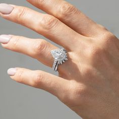 a woman's hand with a diamond ring on top of her finger and the other hand holding an engagement ring