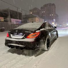 a black car driving down a snow covered street