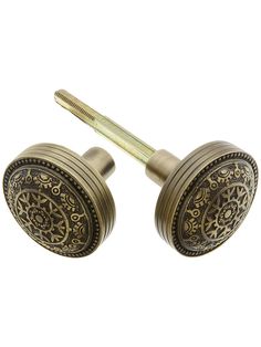 two antique brass knobs with intricate designs on them, one has a screw in the middle