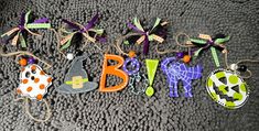 the word baby spelled out in different colors and shapes on a gray surface with halloween decorations