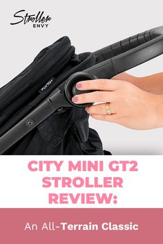 a person holding onto a stroller with the text city mini gt2 stroller review an all - terrain classic