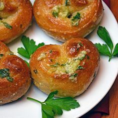 four bread rolls with cheese and herbs on a white plate, ready to be eaten