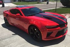 a red chevrolet camaro is parked on the street