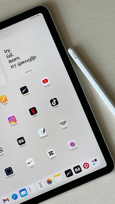 an ipad with icons displayed on the screen and a pen resting on top of it