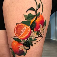 a woman's thigh with oranges and flowers on it