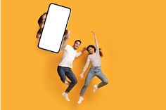 two people jumping in the air while holding up a cell phone with an empty screen