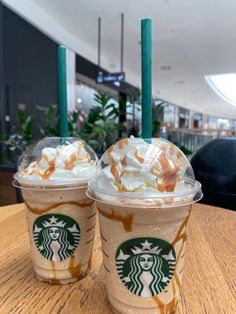 two starbucks drinks sitting on top of a wooden table