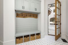 a mud room with white cabinets and baskets