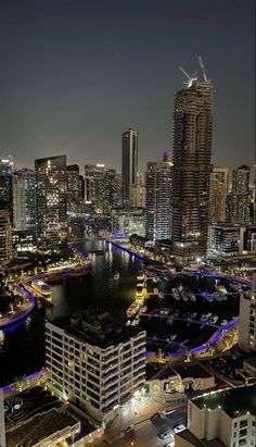 an aerial view of a city at night with boats in the water and buildings lit up