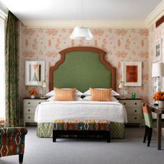 a bedroom with a green headboard and floral wallpaper on the walls, along with an upholstered bed