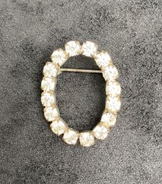 Presented for sale is a vintage Mid-Century oval rhinestone brooch.  The delicate, gorgeous brooch is a collection of white rhinestones arranged in an oval shape and set in a silver-tone metal.  The brooch measures 1.25 inches across the longest section.  The brooch has a three dimensional display.  This elegant brooch is a classic, timeless style that will stand out on any occasion.  The condition is very good.  This brooch is a perfect accent piece for any outfit at any time and a superb gift! Luxury Oval Brooch For Anniversary, Luxury Oval Wedding Brooch, Luxury Vintage Oval Brooch, Luxury Oval Brooches For Wedding, Luxury Classic Oval Brooch, White Oval Brooch For Formal Occasions, White Oval Brooch For Anniversary, Vintage Oval Rhinestone Jewelry, Elegant Brooch