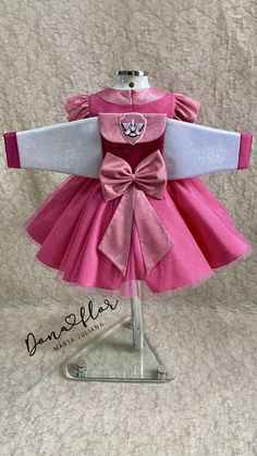 the dress is pink and white with a cat on it's chest, and has a bow at the waist