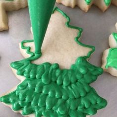 decorated cookies with green icing are on a tray