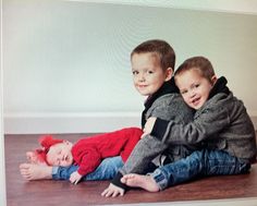 two young boys sitting on the floor with their arms around each other