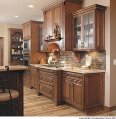 a kitchen with wooden cabinets and tile backsplash, wood flooring and counter tops