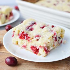 a close up of a piece of cake on a plate with cherries around it