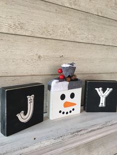 three wooden blocks decorated with christmas decorations and snowman's head on top of each block