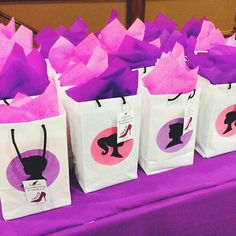 several bags with different designs on them sitting on a purple table cloth covered tablecloth