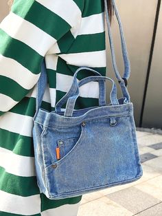 a woman carrying a blue jean purse on her shoulder and wearing a green striped shirt