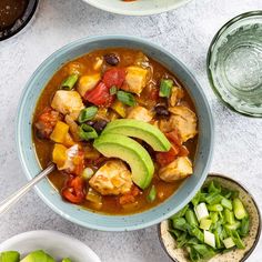 a bowl of chicken tortilla soup with avocado and tomatoes