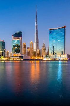 the city skyline is lit up at night, with skyscrapers in the foreground