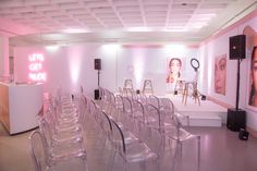 a room filled with lots of clear chairs next to a white counter and pink walls