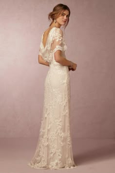 a woman in a wedding dress standing with her back to the camera