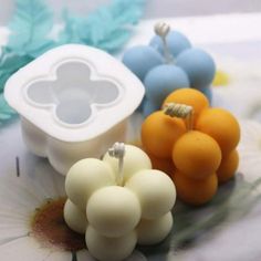 three fruit shaped candles sitting on top of a flowered tablecloth with blue and white flowers