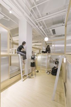 two people standing on ladders in a room with bunk beds